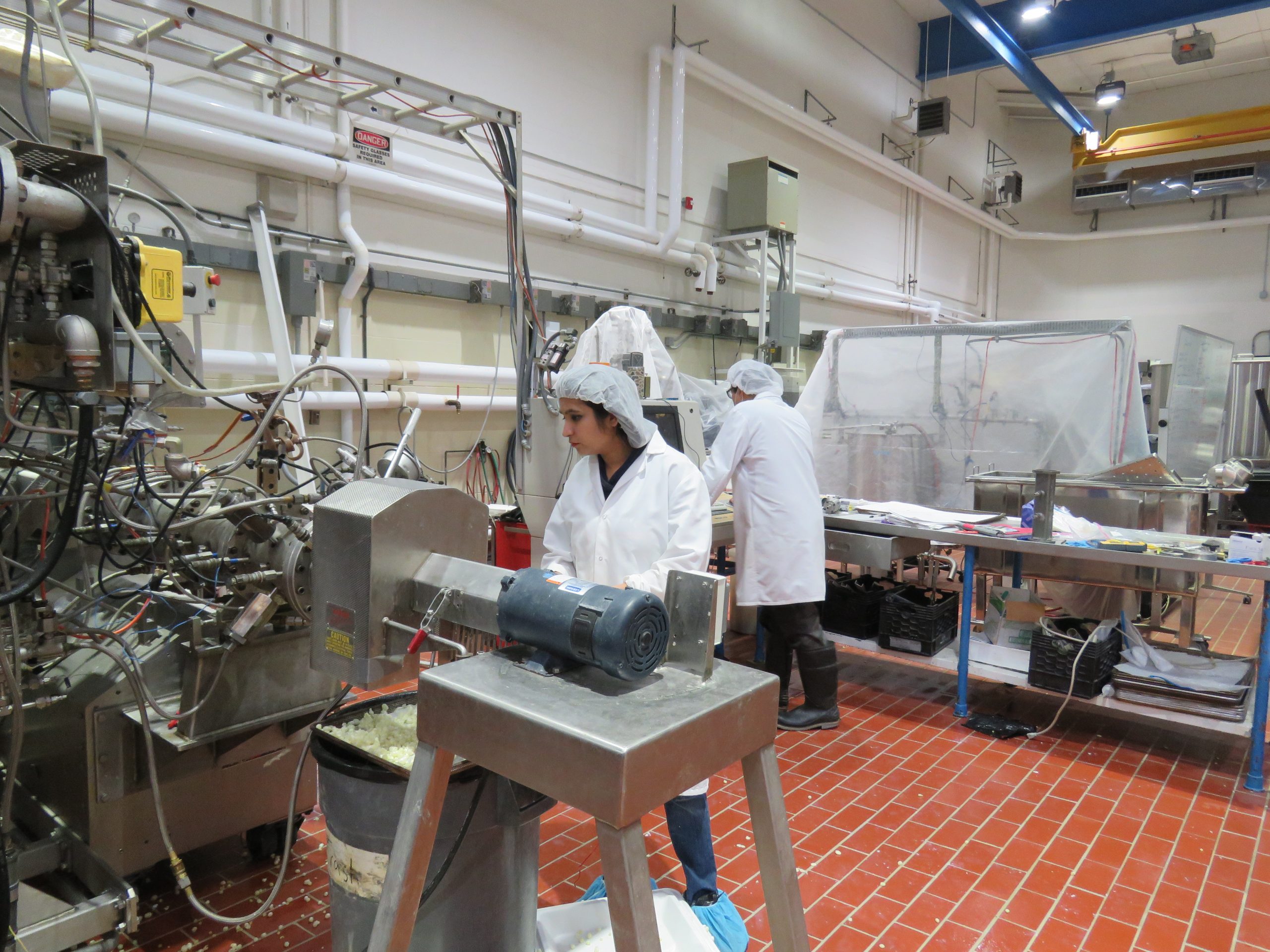 Woman standing at an extruder machine