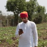 A farmer looking at a mobile phone