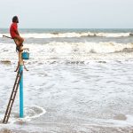 A man on a ladder staring at the sea