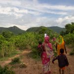 Women and children walking on a farm