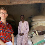 Anthony Wenndt posing with a man sitting on bags of grain