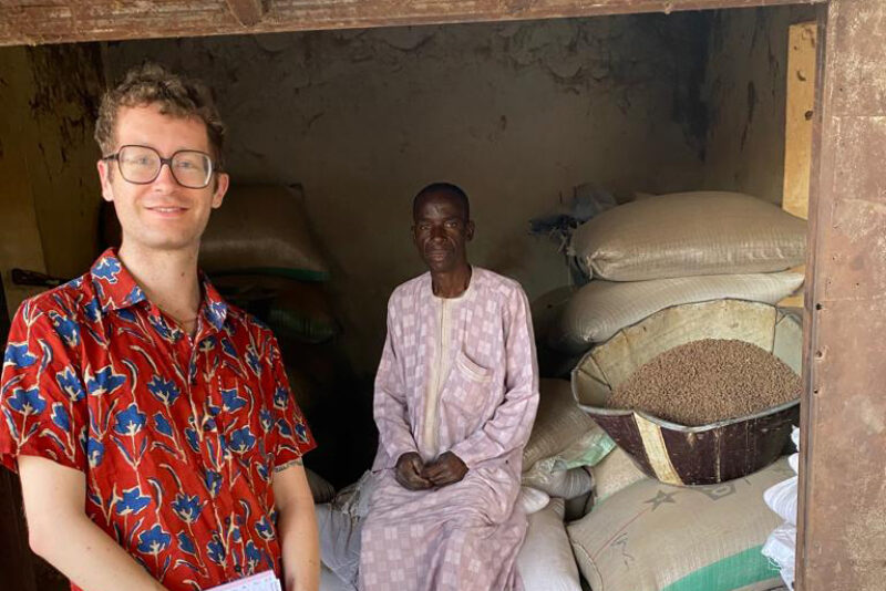 Anthony Wenndt posing with a man sitting on bags of grain