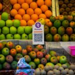 A UPI QR code sitting amongst fruit in a market stall