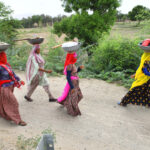 A group of women walking on a road with work supplies