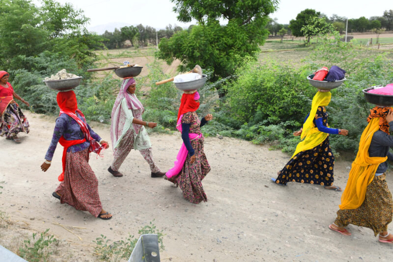 A group of women walking on a road with work supplies
