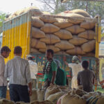 Men standing in front of a truck loaded with bags of pulses