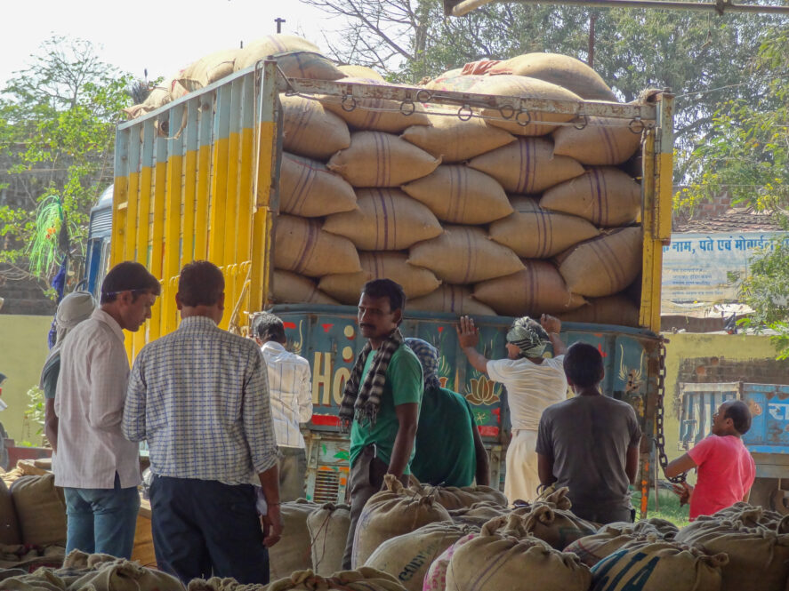 Men standing in front of a truck loaded with bags of pulses