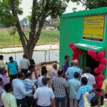 People standing around a green pump house at the inauguration of TCI's agrivoltaics site in Bihar