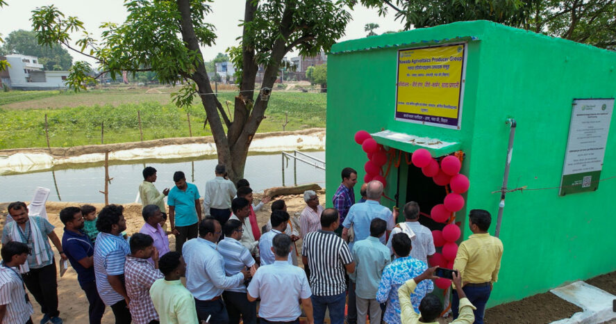 People standing around a green pump house at the inauguration of TCI's agrivoltaics site in Bihar