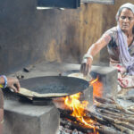 Two women cooking flatbreads in a pan over an open fire