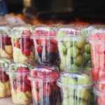 Grapes, strawberries, and cut pineapple stored in round plastic containers
