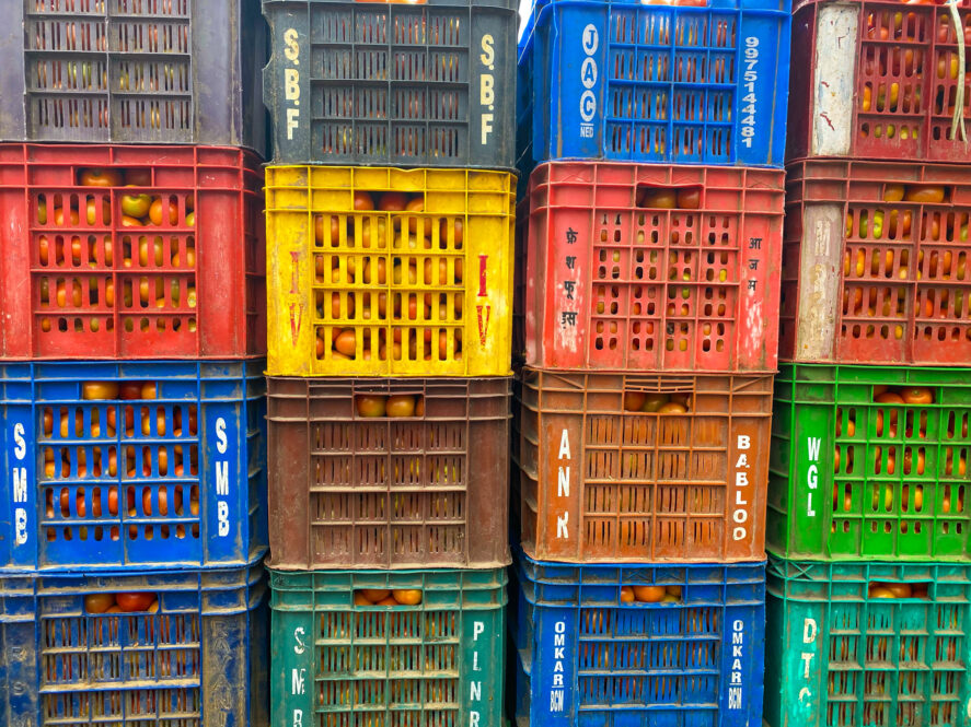 A wall of colorful plastic crates filled with tomatoes
